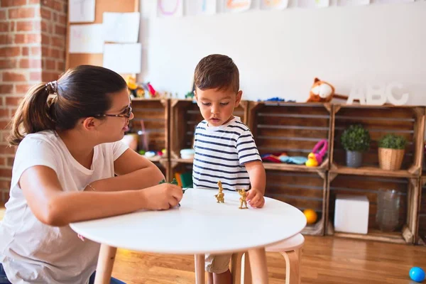 stock image Beautiful teacher and toddler boy playing with figurine army soldiers at kindergarten