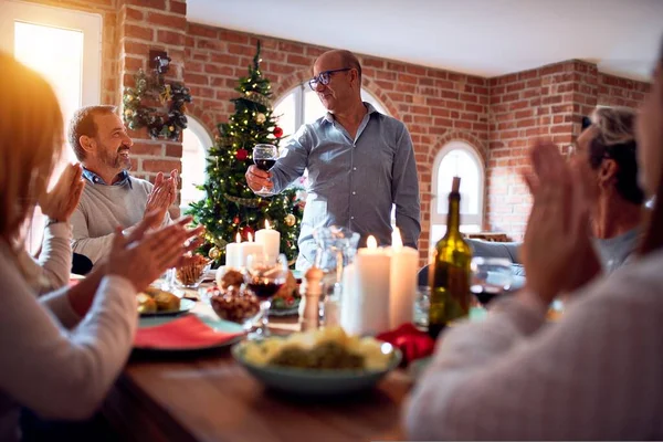 Family and friends dining at home celebrating christmas eve with traditional food and decoration, making a toast for new year best wishes