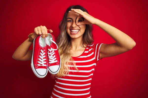 Jeune Belle Femme Tenant Des Baskets Sur Fond Rouge Isolé — Photo