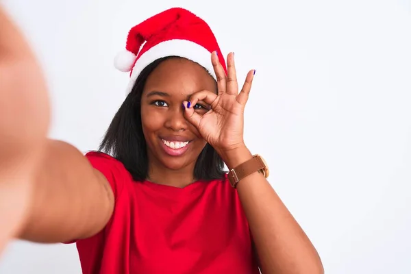 年轻的非洲裔美国女人头戴圣诞礼帽 在孤立的背景下自拍 笑容满面 手牵手看着手指 做好手势 — 图库照片