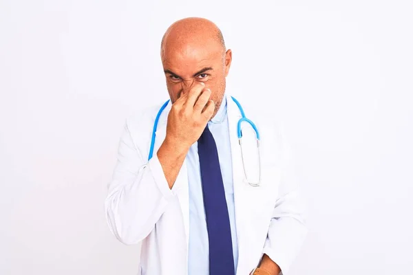 中年男人戴着听诊器 打着领带 站在孤立的白色背景上 闻到一股难闻 无法忍受的气味 用手指捂住鼻子屏住呼吸 臭味概念 — 图库照片