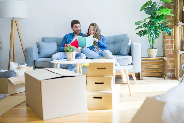 Pareja joven relajándose en el sofá leyendo un libro, tomando un descanso — Foto de Stock