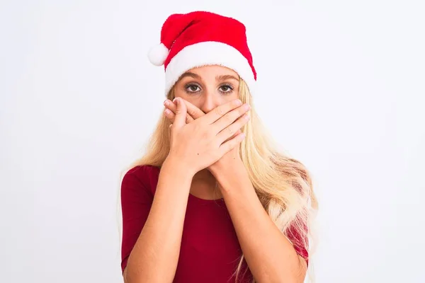 孤立した白い背景の上にクリスマスのサンタの帽子を身に着けている若い美しい女性は間違いのための手で口を覆うショックを受けた 秘密概念 — ストック写真