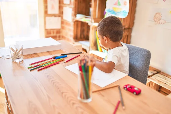 美しいアフリカ系アメリカ人の幼児は 幼稚園で机の上に紙と鉛筆を使って絵を描く — ストック写真