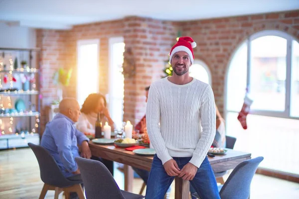 幸せと自信に満ちた若いハンサムな男 家で家族と一緒にクリスマスを祝うサンタの帽子をかぶって — ストック写真