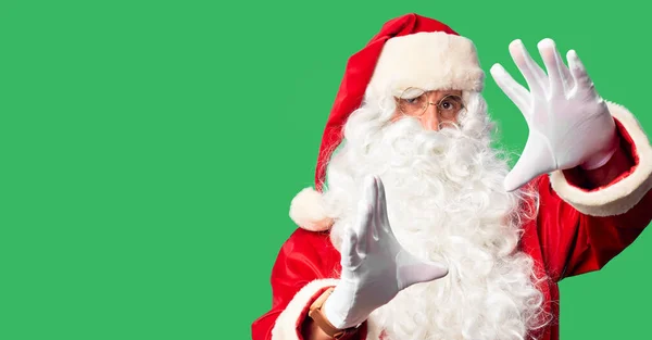 中年男子 身穿圣诞老人服装 蓄着胡子 站在那里 用手心和手指头 用相机透视画框 — 图库照片