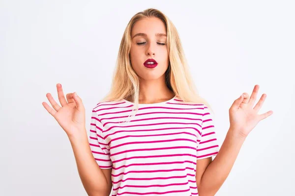年轻美丽的女人穿着粉色条纹T恤 站在孤立的白色背景上 闭上双眼 用手指做冥想动作 瑜伽概念 — 图库照片