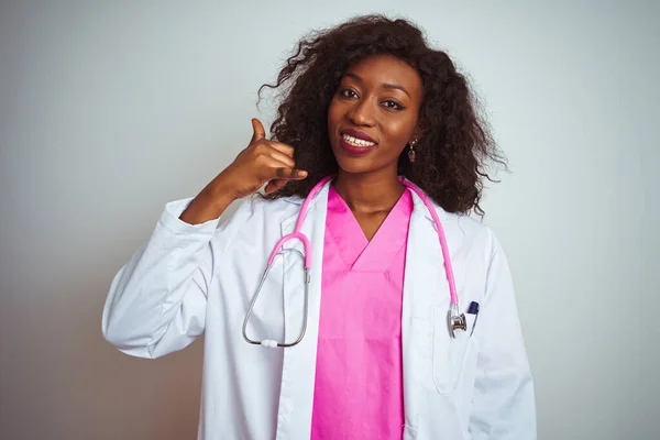 아프리카 미국인 의사는 분홍빛 청진기를 착용하고 손가락으로 통화를 것처럼 미소를 — 스톡 사진