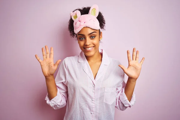 年轻的非洲裔美国女人 身穿睡衣 戴着面具 披着孤立的粉色背景 带着十号手指 面带微笑 自信而快乐 — 图库照片