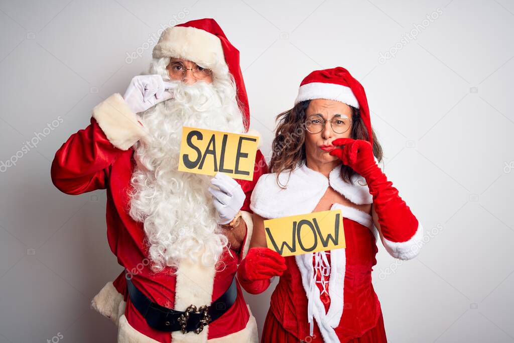 Couple wearing Santa costume holding wow and sale banner over isolated white background mouth and lips shut as zip with fingers. Secret and silent, taboo talking