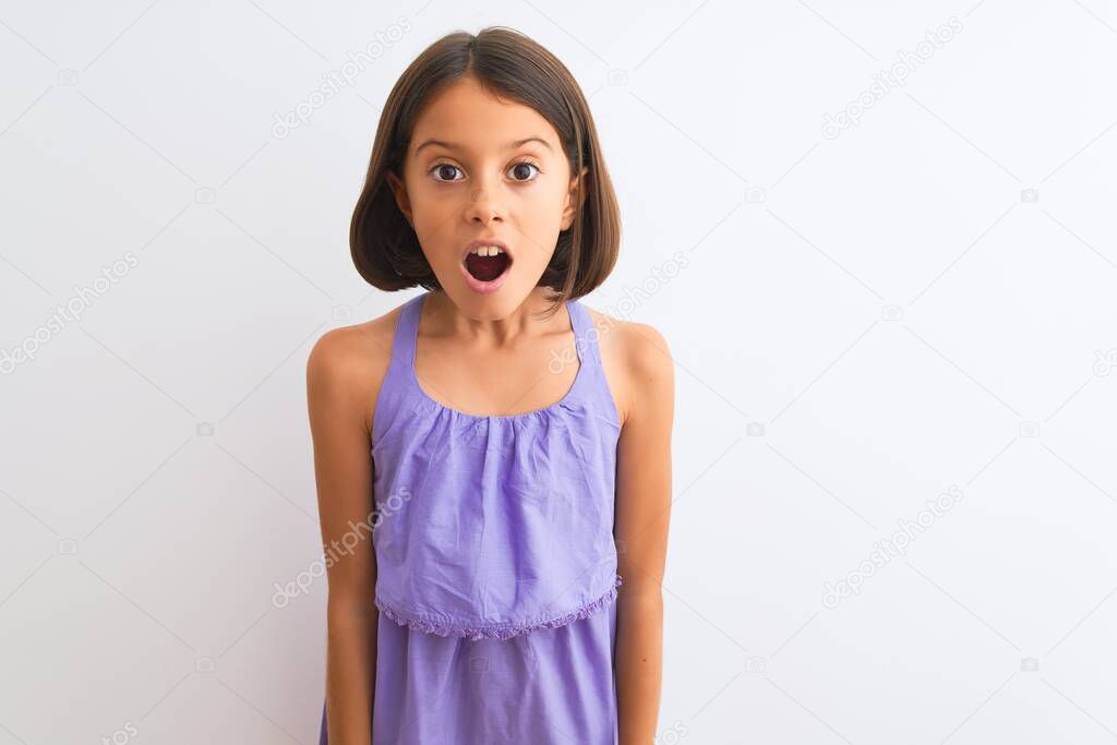 Young beautiful child girl wearing purple casual dress standing over isolated white background afraid and shocked with surprise expression, fear and excited face.