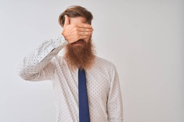 Genç kızıl saçlı İrlandalı işadamı izole edilmiş beyaz arka planda duruyor. Gülümsüyor ve gülümsüyor. Yüzünde şaşkınlık için gözleri örtüyor. Kör kavram.