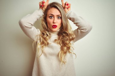 Kışın balıkçı yaka kazak giyen güzel bir kadın izole edilmiş beyaz arka plan üzerine komik hareketler yapıyor.