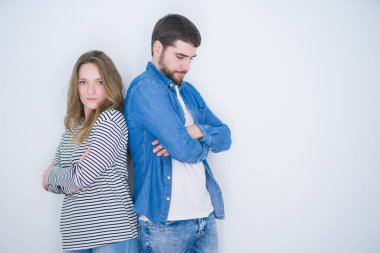 Genç güzel çift beyaz izole arka plan şüpheci ve sinir üzerinde birlikte ayakta, çapraz kolları ile yüzünde ifade onaylamayan. Negatif kişi.