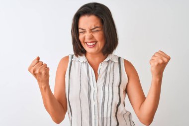 İzole edilmiş beyaz arka plan üzerinde duran sıradan çizgili tişört giyen genç ve güzel bir kadın mutlu ve heyecanlı bir şekilde kollarını kaldırıp, gülümseyerek ve başarı için çığlık atarak zafer jesti yapıyor. Kutlama konsepti.