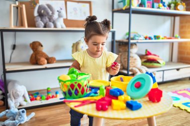 Anaokulunda plastik sebzeler ve tabaklarla masada oynayan güzel bir çocuk.