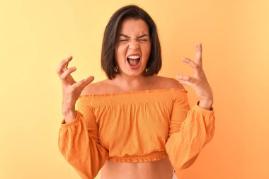 İzole edilmiş turuncu arka plan üzerinde dikilen genç ve güzel bir kadın başarının çılgınlığını kollarını kaldırarak ve gözlerini kapayarak heyecanla haykırarak kutluyor. Kazanan konsept