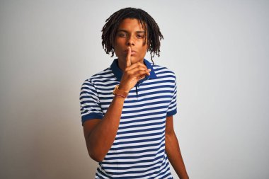 Sarı çizgili mavi polo giyen Afro bir adam izole edilmiş beyaz arka planda dikiliyor ve parmakları dudaklarında sessiz olmak istiyor. Sessizlik ve gizli konsept.