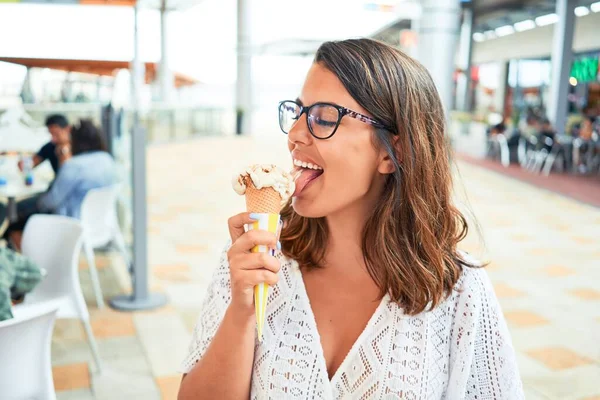 Young beautiful woman eating ice cream cone at the shopping center on a sunny day of summer on holidays