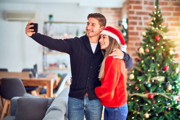 年轻漂亮的夫妇面带微笑 既快乐又自信 在家里的圣诞树下 站着拥抱让自己靠相机拍成电影 — 图库照片
