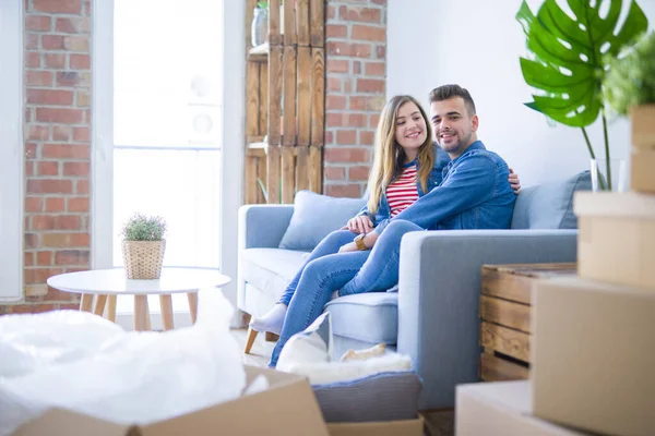 Junges schönes Paar sitzt und umarmt auf dem Sofa bei neuen ap — Stockfoto