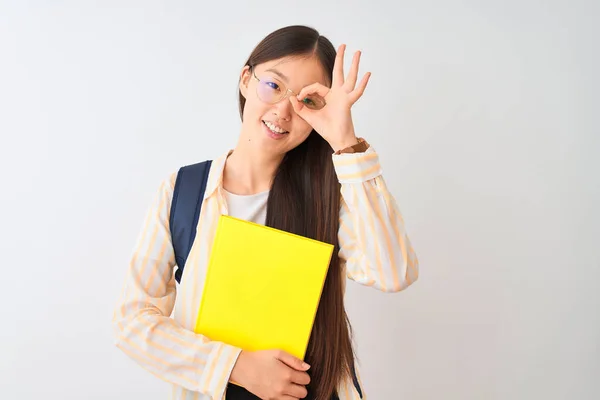 Chinese student woman wearing glasses backpack book over isolated white background with happy face smiling doing ok sign with hand on eye looking through fingers
