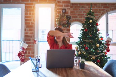 Masada oturan güzel bir kadın evde dizüstü bilgisayarla çalışıyor Noel ağacının etrafında kollarıyla gözlerini kapatıyor, ciddi ve üzgün görünüyor. Görme, saklama ve reddetme konsepti