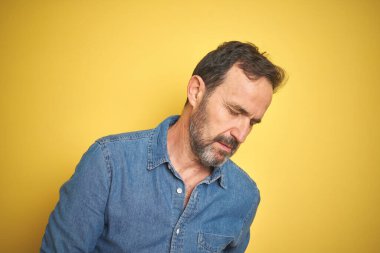 Yakışıklı, orta yaşlı, gri saçlı, izole edilmiş sarı arka planı olan, midesi bulanan, acı verici bir hastalığı olan bir adam. Ache kavramı.