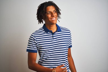 Sarı çizgili mavi polo giyen Afro bir adam izole edilmiş beyaz arka planda dikilip yüzünde gülümseme, doğal bir ifade ile bir o yana bir bu yana bakıyor. Kendinden emin gülen.