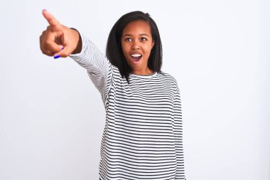 Güzel, genç, Afro-Amerikalı bir kadın kışın giydiği süveter ile izole edilmiş arka planda parmakla işaret ederek ileriyi işaret ediyor, ağzı açık, şaşırmış, ön tarafta bir şey var.