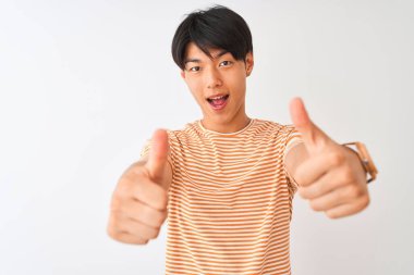 Sıradan çizgili tişört giyen genç Çinli adam izole edilmiş beyaz arka planda duruyor. Elle olumlu jest yapıyor, gülümsüyor ve başarı için mutlu. Kazanan jest.