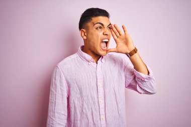 Tecrit edilmiş pembe arka planda dikilen Brezilyalı genç adam el ele tutuşarak bağırıyor ve çığlık atıyordu. İletişim konsepti.