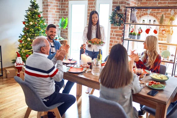 Beautiful family meeting smiling happy and confident. Person standing holding roasted turkey celebrating Christmas at home