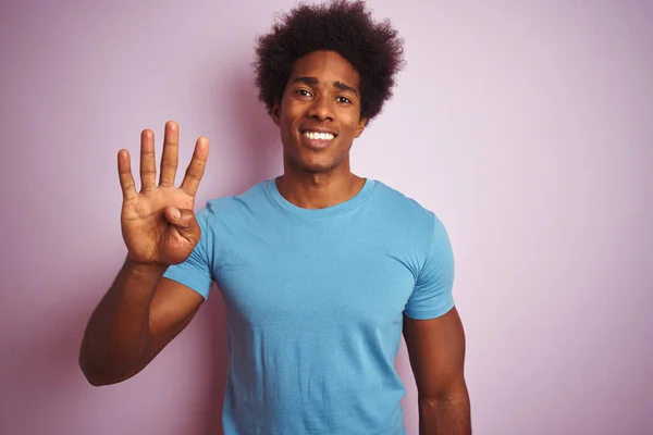 アフリカ系アメリカ人男性とアフロの髪を身に着けている青Tシャツ上に立って隔離されたピンクの背景を示すと指の数4で指摘しながら 自信と幸せ — ストック写真