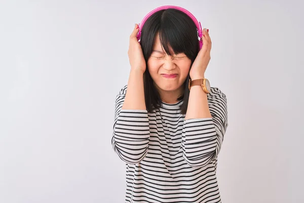 中国妇女在孤独的白色背景下 用粉色耳机听音乐 因疼痛和偏头痛而感到绝望和压力 手放在头上 — 图库照片