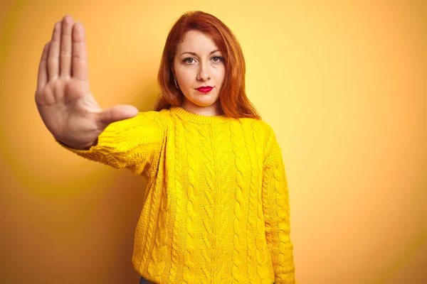 美丽的红头发女人穿着冬季毛衣站在孤立的黄色背景上 手心停止歌唱 脸上带有消极而严肃的手势的警告表情 — 图库照片