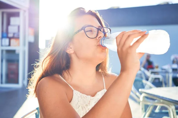 年轻美丽的女人坐在餐馆里享受暑假 喝着一瓶水 — 图库照片
