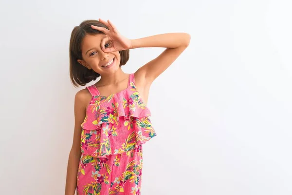 年轻美丽的小女孩穿着粉红色的花裙子 站在孤独的白色背景上 做着手势 微笑着 用手指看着 脸上洋溢着幸福的表情 — 图库照片