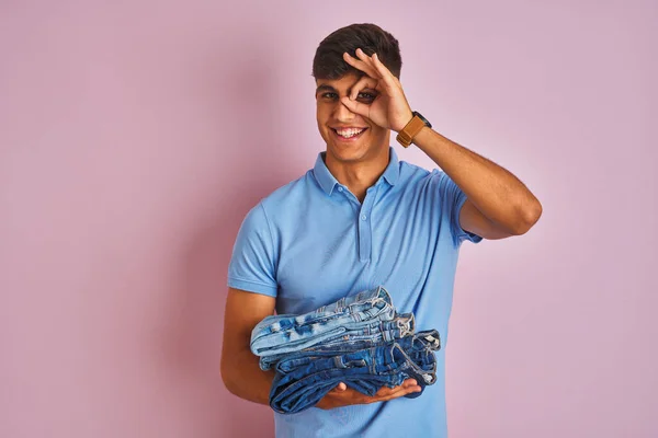 Jovem Indiana Lojista Homem Segurando Dobrado Jeans Sobre Isolado Rosa — Fotografia de Stock