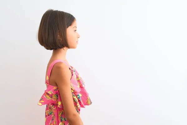 年轻美丽的小女孩穿着粉红色的花衣站在孤零零的白色背景上 望着旁边 带着自信的微笑放松自己的姿态 — 图库照片