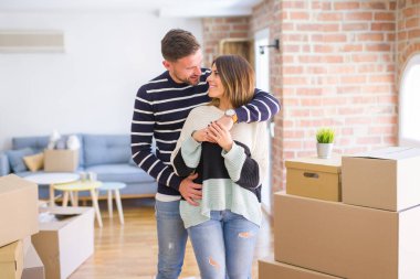 Karton kutular etrafında yeni evde sarılma genç güzel çift