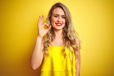 Sarı izole arka planda duran tişört giyen genç saldırgan kadın el ve parmaklarıyla 