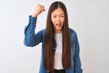 İzole edilmiş beyaz arka plan üzerinde duran genç Çinli kadın kızgın ve öfkeliydi. Öfkeyle bağırırken yumruğunu kaldırıyordu. Öfke ve agresif kavram.