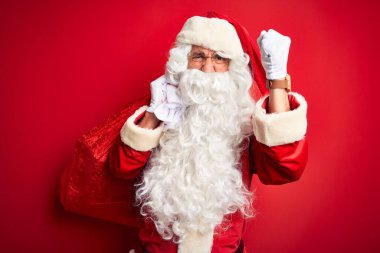 Orta yaşlı bir adam Noel Baba kostümü giyiyor. Elinde hediyeler var. Kırmızı arka planda. Sinirli ve sinirli bir şekilde bağırıyor.