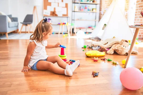 若いです美しいですブロンド女の子楽しいです学校でおもちゃで遊びます幼稚園 笑顔幸せな遊びとともに知性おもちゃとともに自宅 — ストック写真