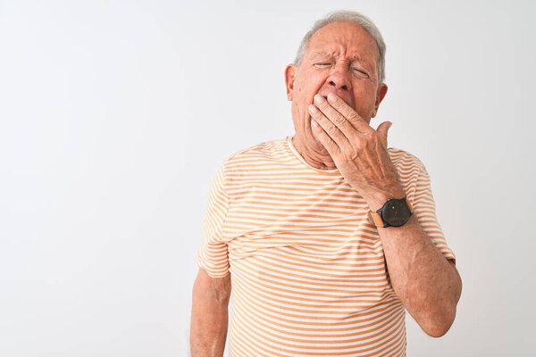 Senior grey-haired man wearing striped t-shirt standing over isolated white background bored yawning tired covering mouth with hand. Restless and sleepiness.