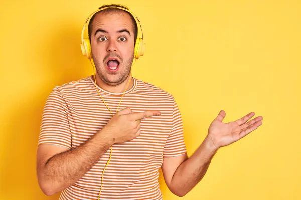 Joven Escuchando Música Usando Auriculares Parados Sobre Fondo Amarillo Aislado — Foto de Stock