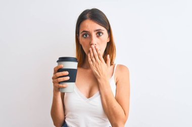 Güzel kızıl saçlı kadın kahve içerken arka plandaki izole edilmiş arka planda, ağzı kapalı, utançtan ağzı açık, korku ifadesi, sessizlikten korkmak, gizli bir konsept.