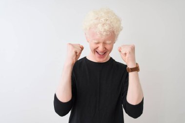 Siyah tişörtlü genç albino bir adam başarılı olmak için heyecanlı kolları havada ve gözleri kapalı zaferi kutlarken gülümsüyor. Kazanan konsept.