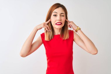 Kırmızılı iş kadını zarif kırmızı elbiseler giyip izole edilmiş beyaz arka planda duruyor. Yüksek sesli müzik sesi için parmaklarıyla kulaklarını kapatıyor. Sağır kavramı.